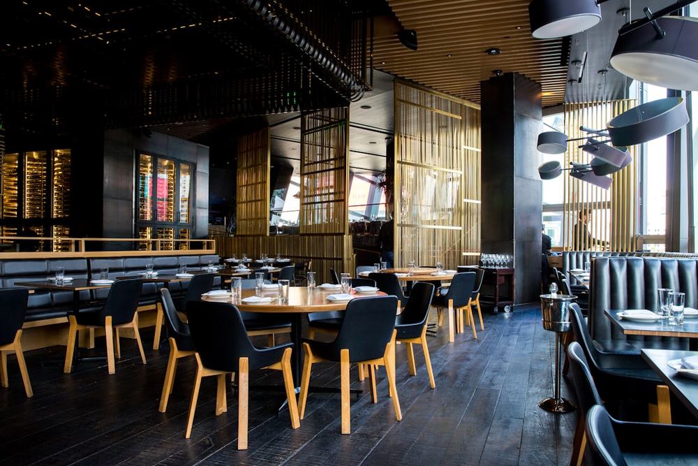 An empty restaurant dining room with tables set and chairs squared up before service